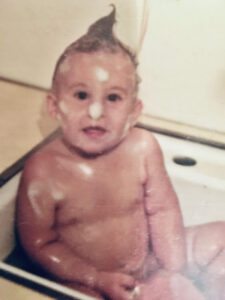 Dr. Clayton as a baby sitting in bathtub with suds on his face.